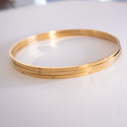 Gold bangles on a white surface