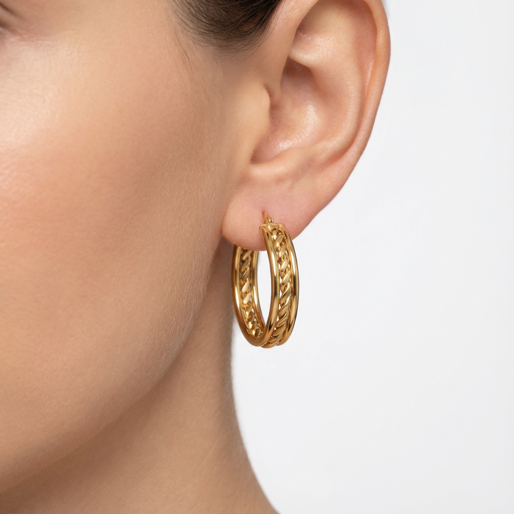 Gold hoop earring worn by a person on a light background