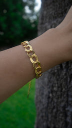 Gold chain bracelet on a wrist with a blurred background