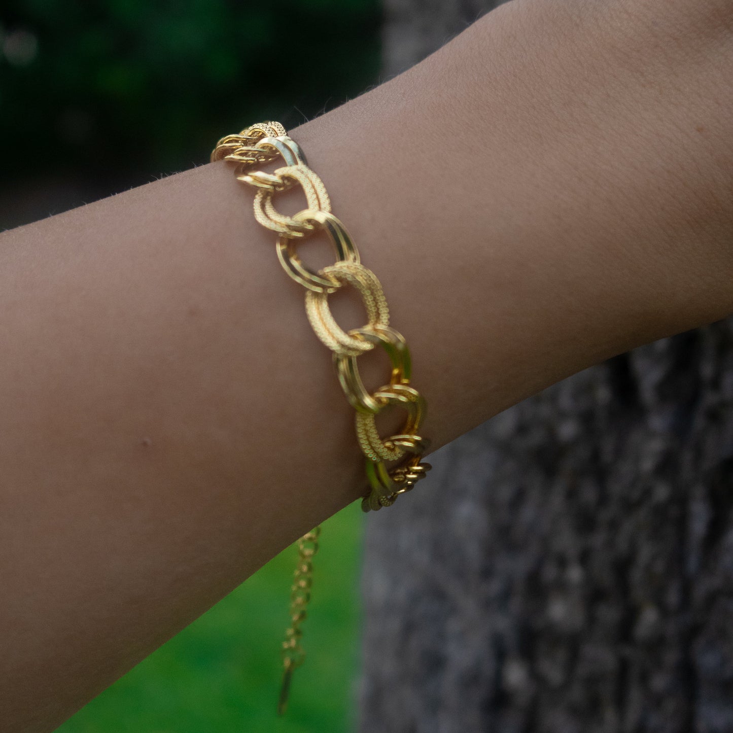 Gold chain bracelet on a wrist with a blurred background