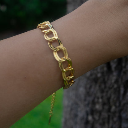 Gold chain bracelet on a wrist with a blurred background