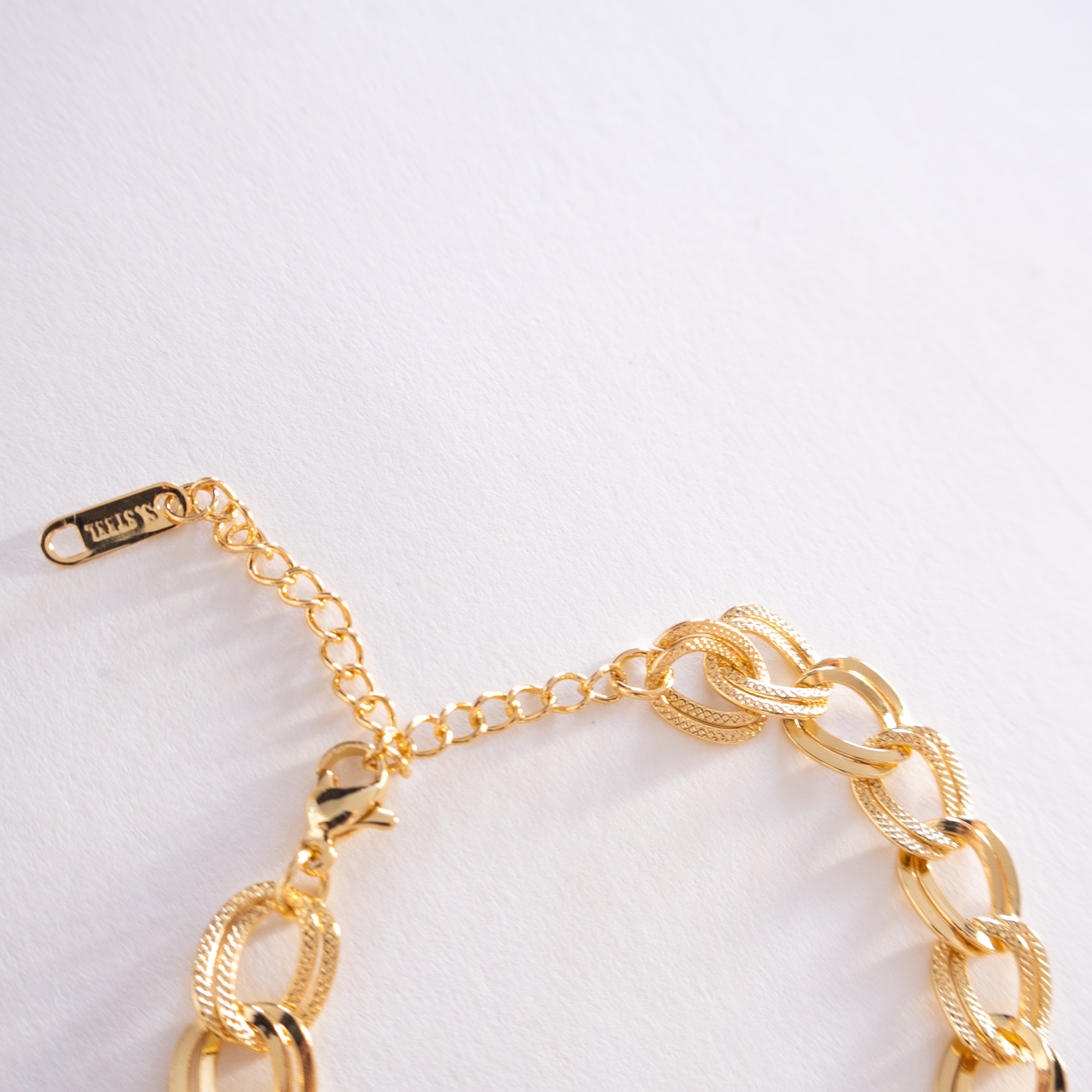 Gold chain bracelet on a light gray background