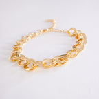 Gold chain bracelet on a light gray background