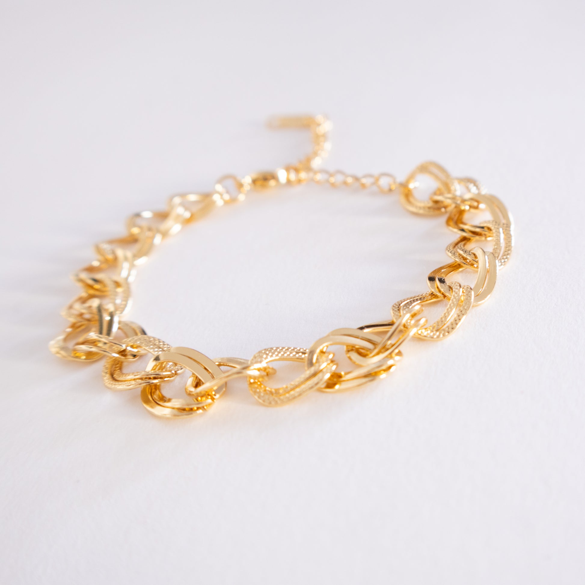 Gold chain bracelet on a light gray background