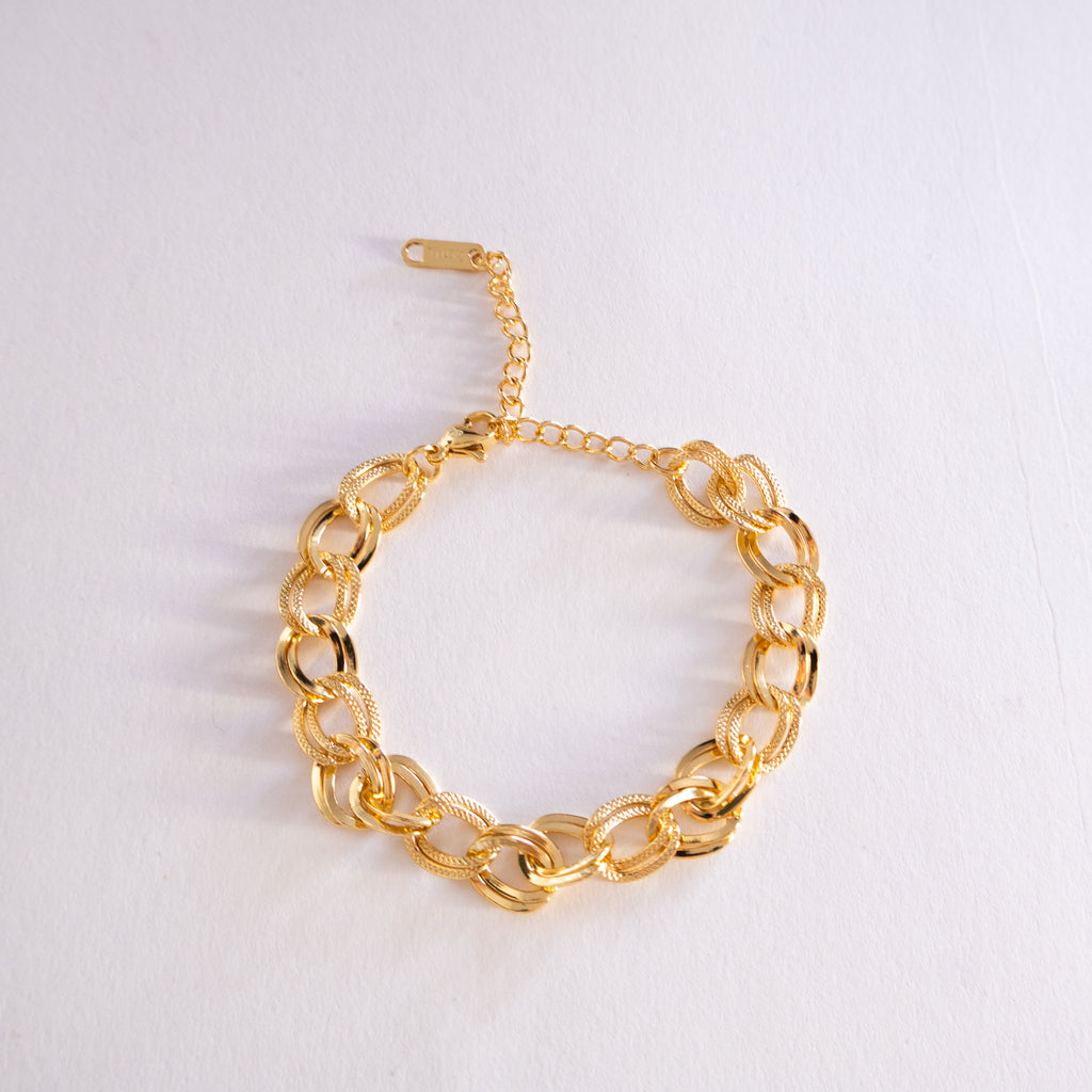 Gold chain bracelet on a light gray background