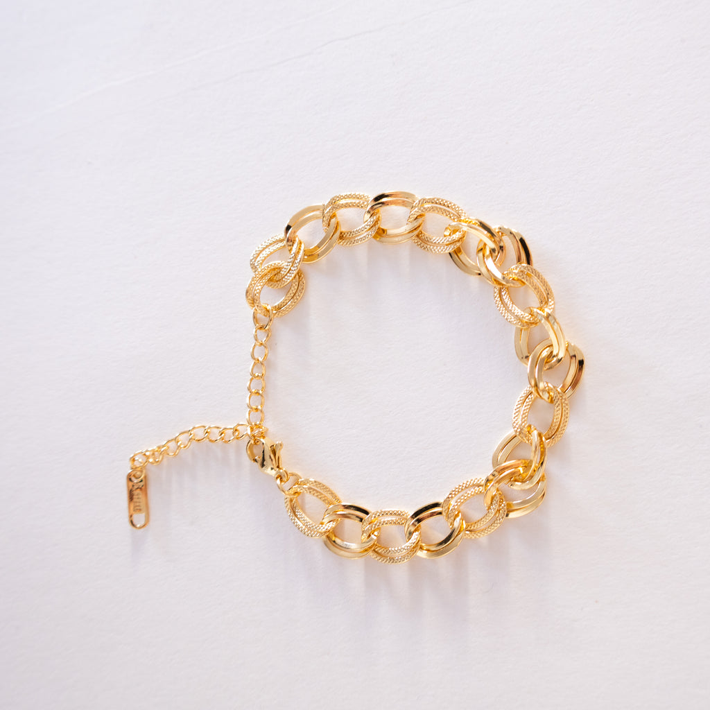 Gold chain bracelet on a light gray background