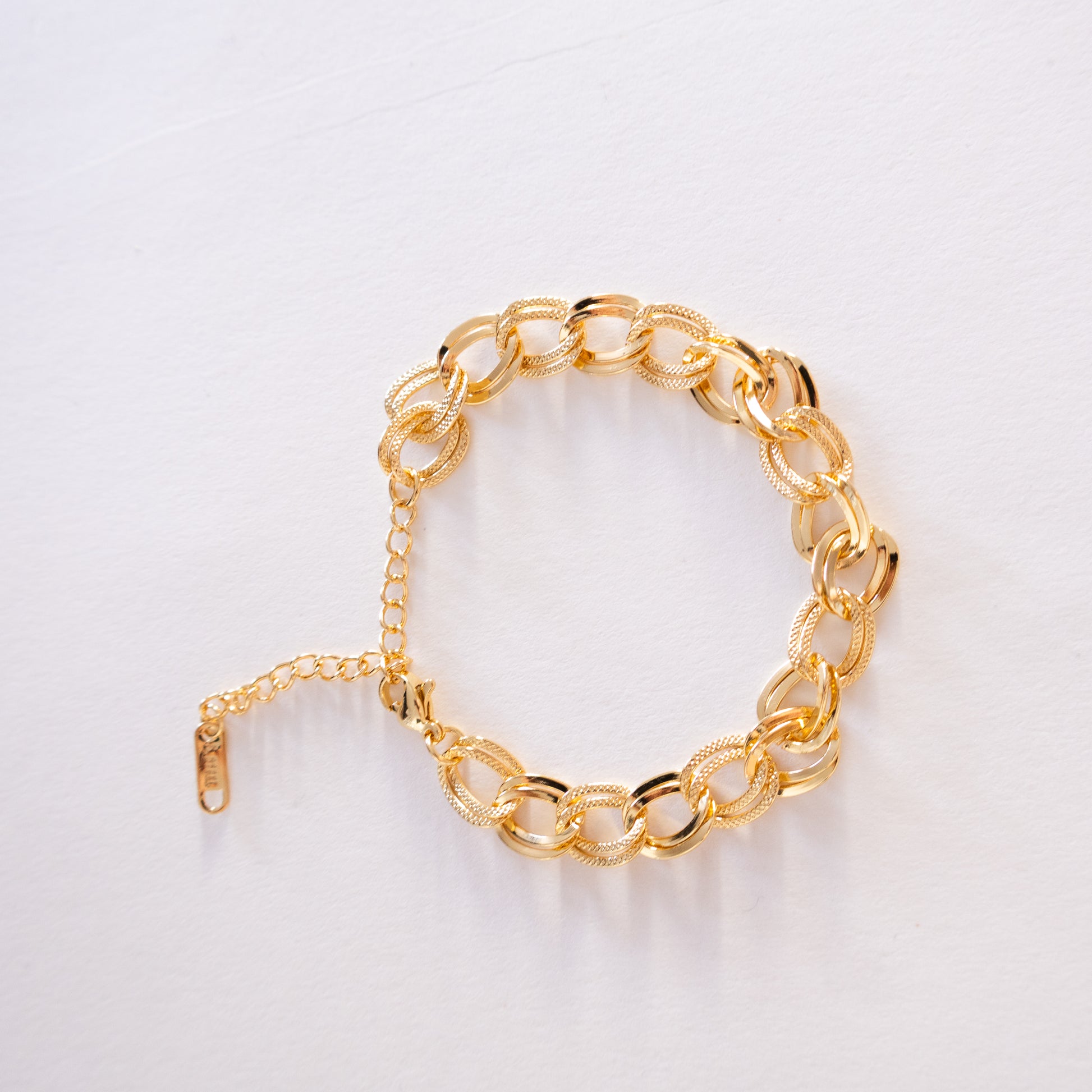 Gold chain bracelet on a light gray background