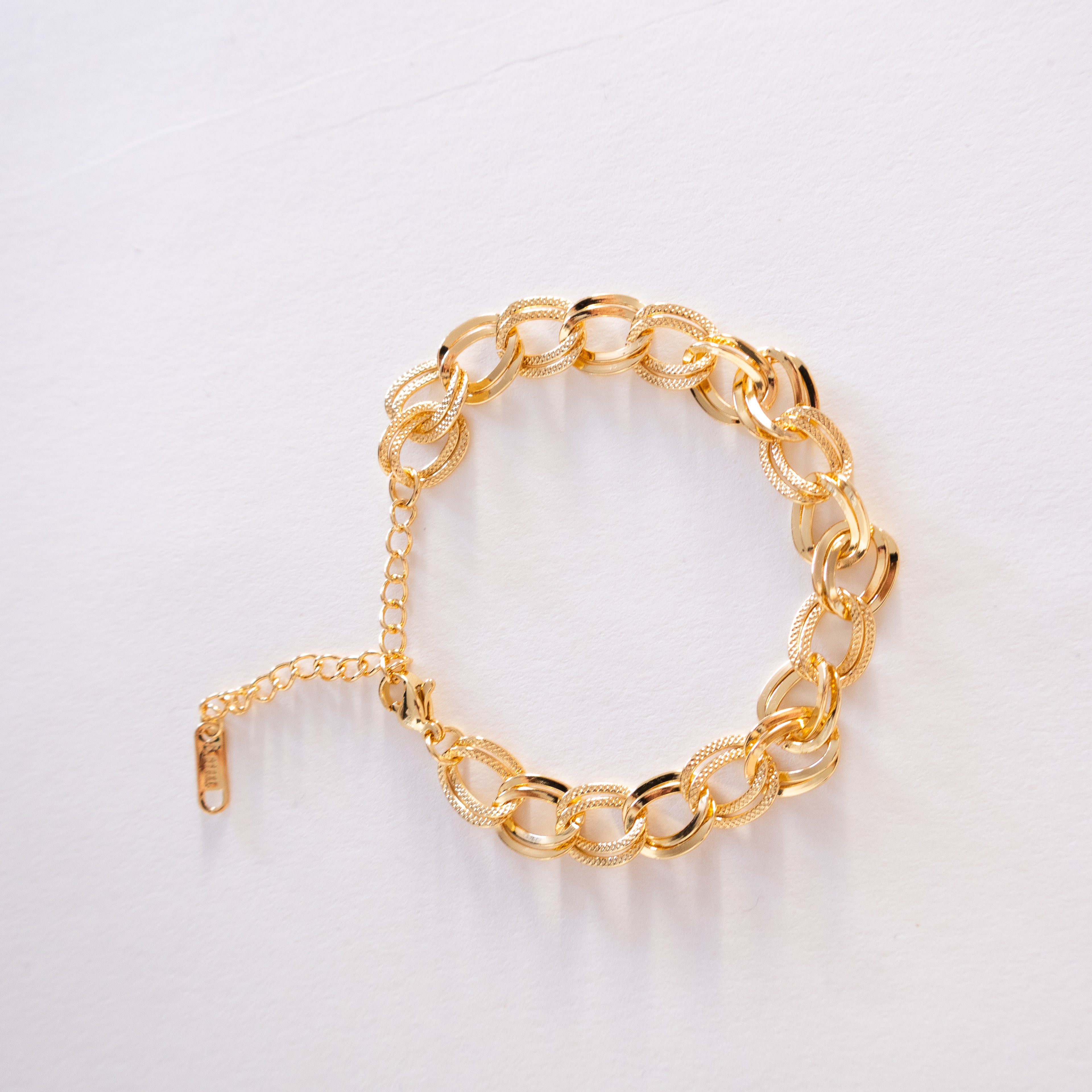 Gold chain bracelet on a light gray background