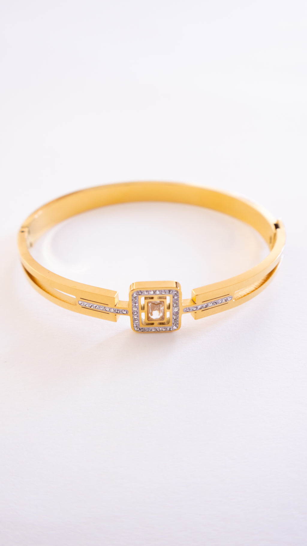 Gold bracelet with a square clasp on a white background