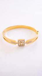 Gold bracelet with a square clasp on a white background