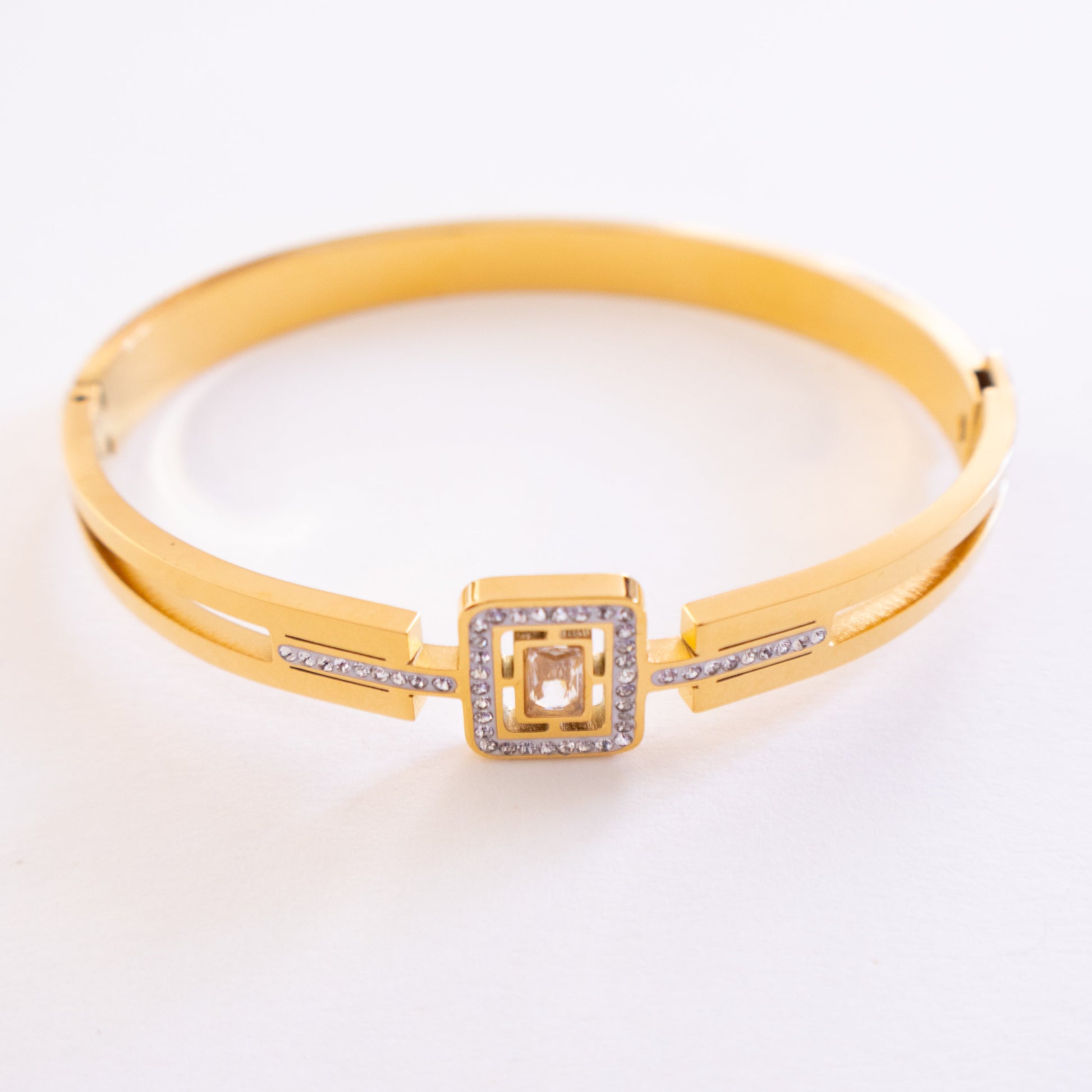 Gold bracelet with a square clasp on a white background