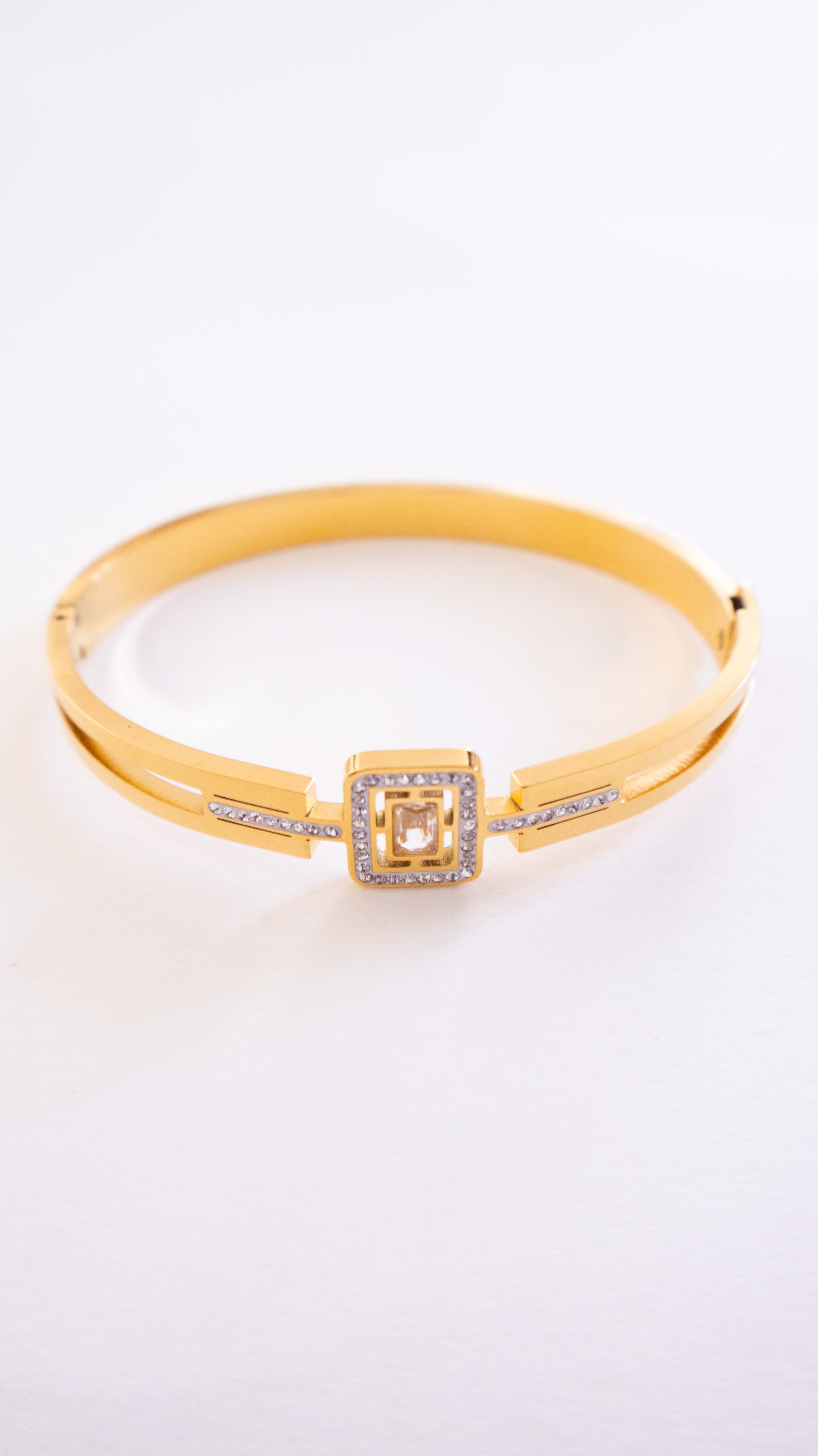 Gold bracelet with a square clasp on a white background