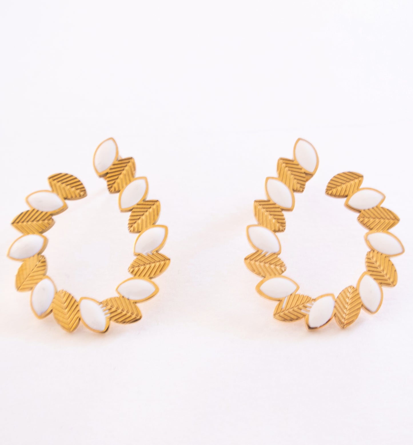 Pair of gold and white hoop earrings on a white background