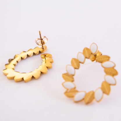 Gold and white earrings on a light background
