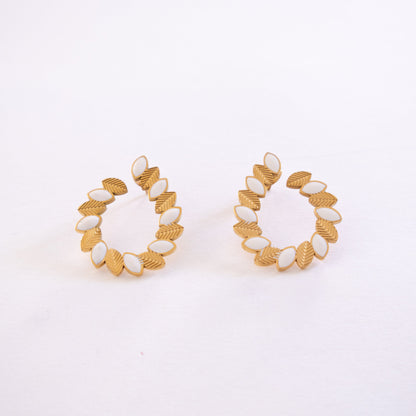 Pair of gold and white hoop earrings on a light gray background