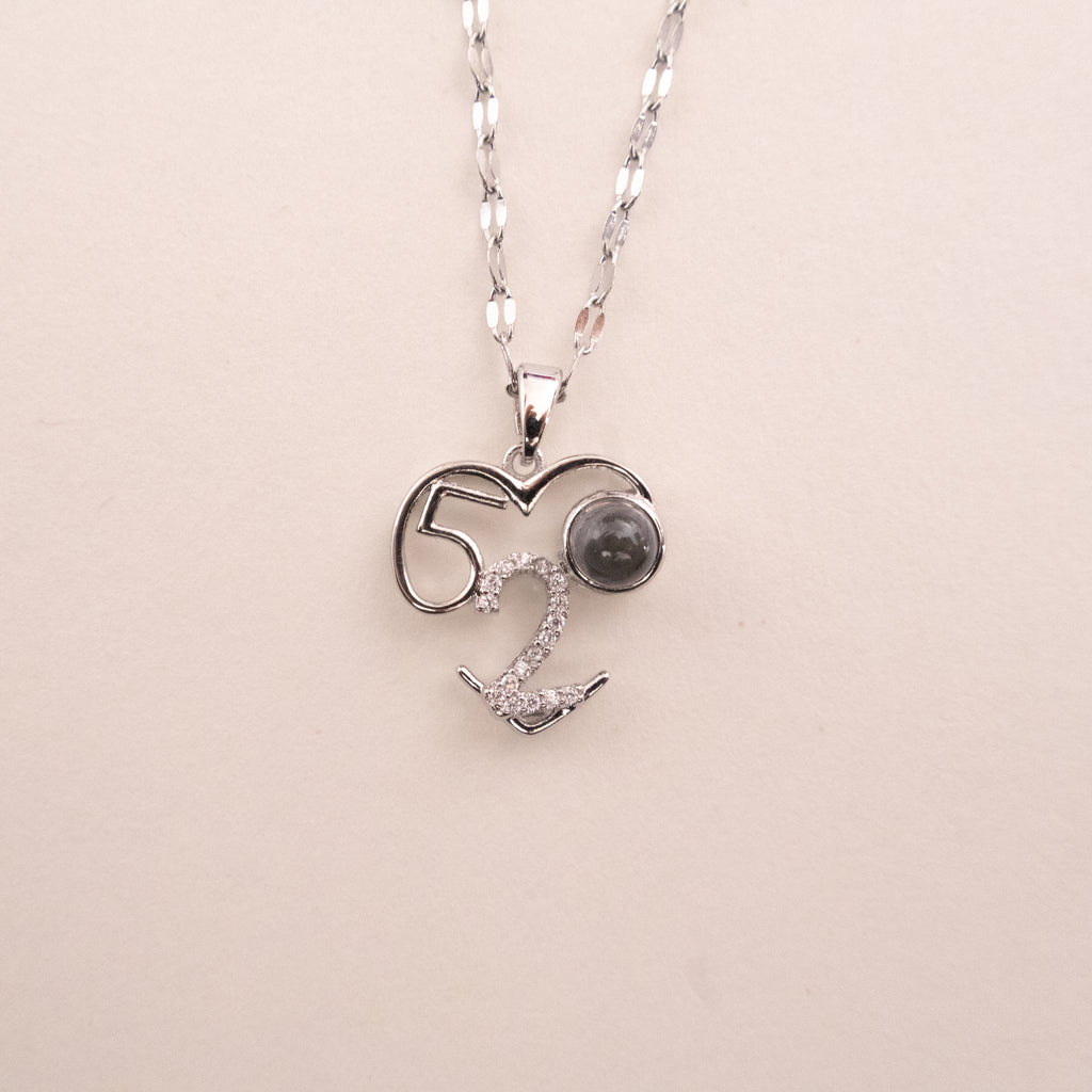 Silver necklace with a heart-shaped pendant on a beige background
