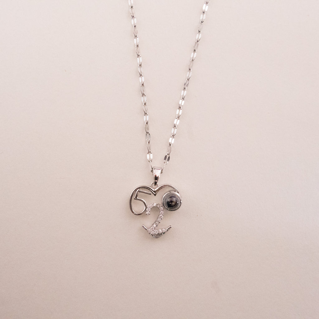 Heart-shaped pendant necklace with 'LOVE' engraving on a beige background