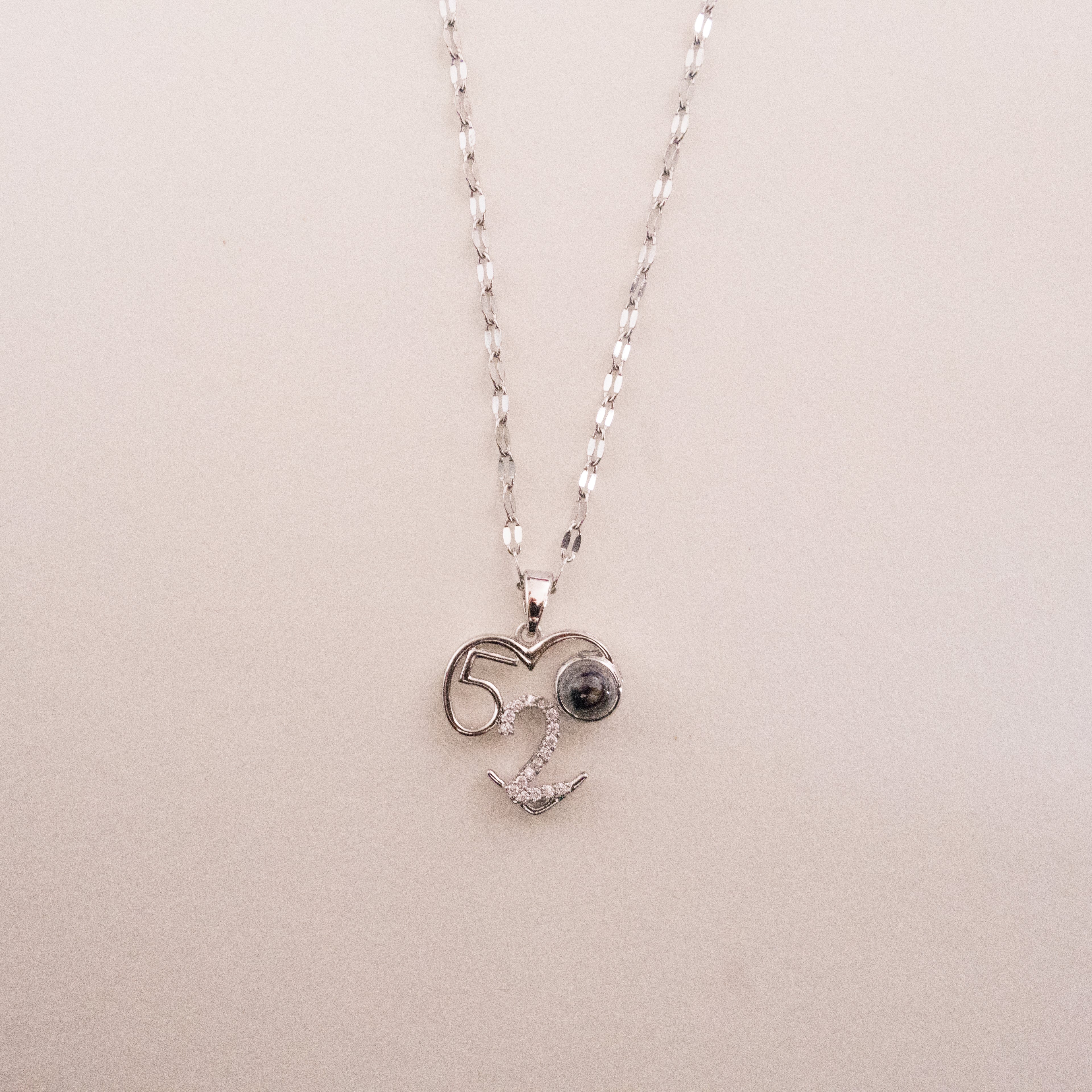 Heart-shaped pendant necklace with 'LOVE' engraving on a beige background