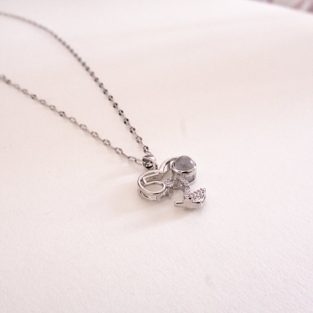 Silver necklace with a unique pendant on a light pink background