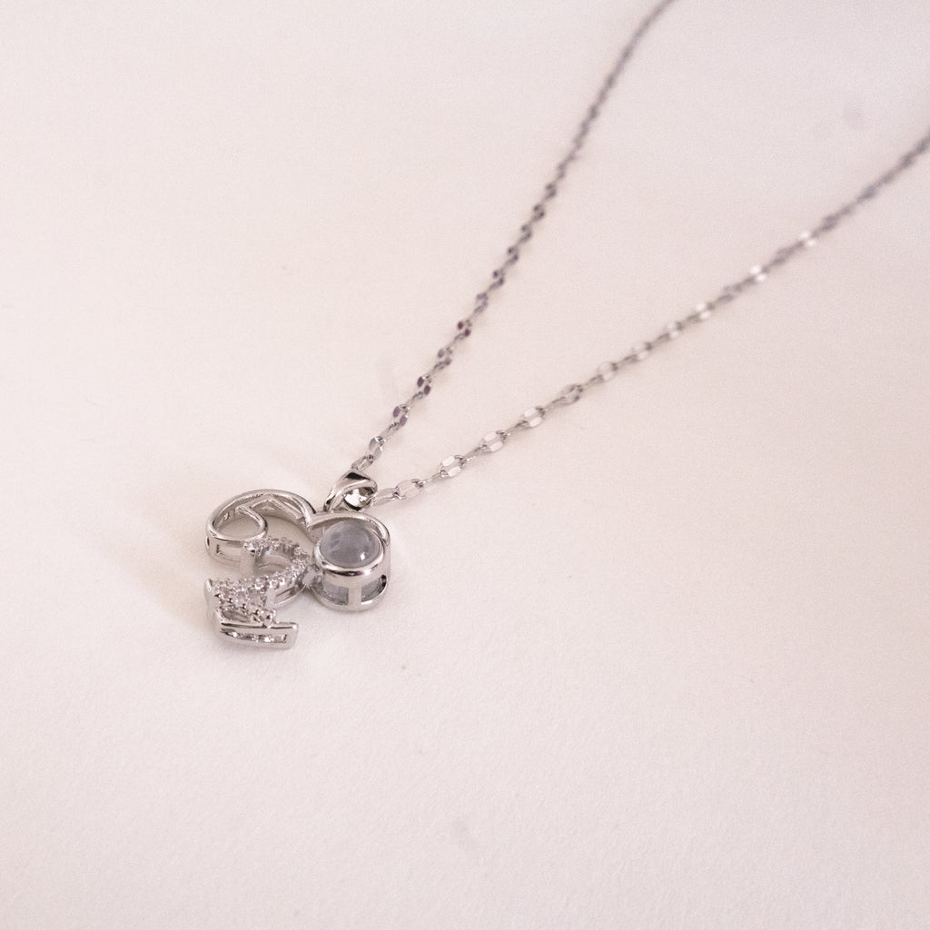 Silver necklace with a bow-shaped pendant on a light pink background