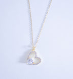 Heart-shaped pendant necklace with a light blue gemstone on a light gray background