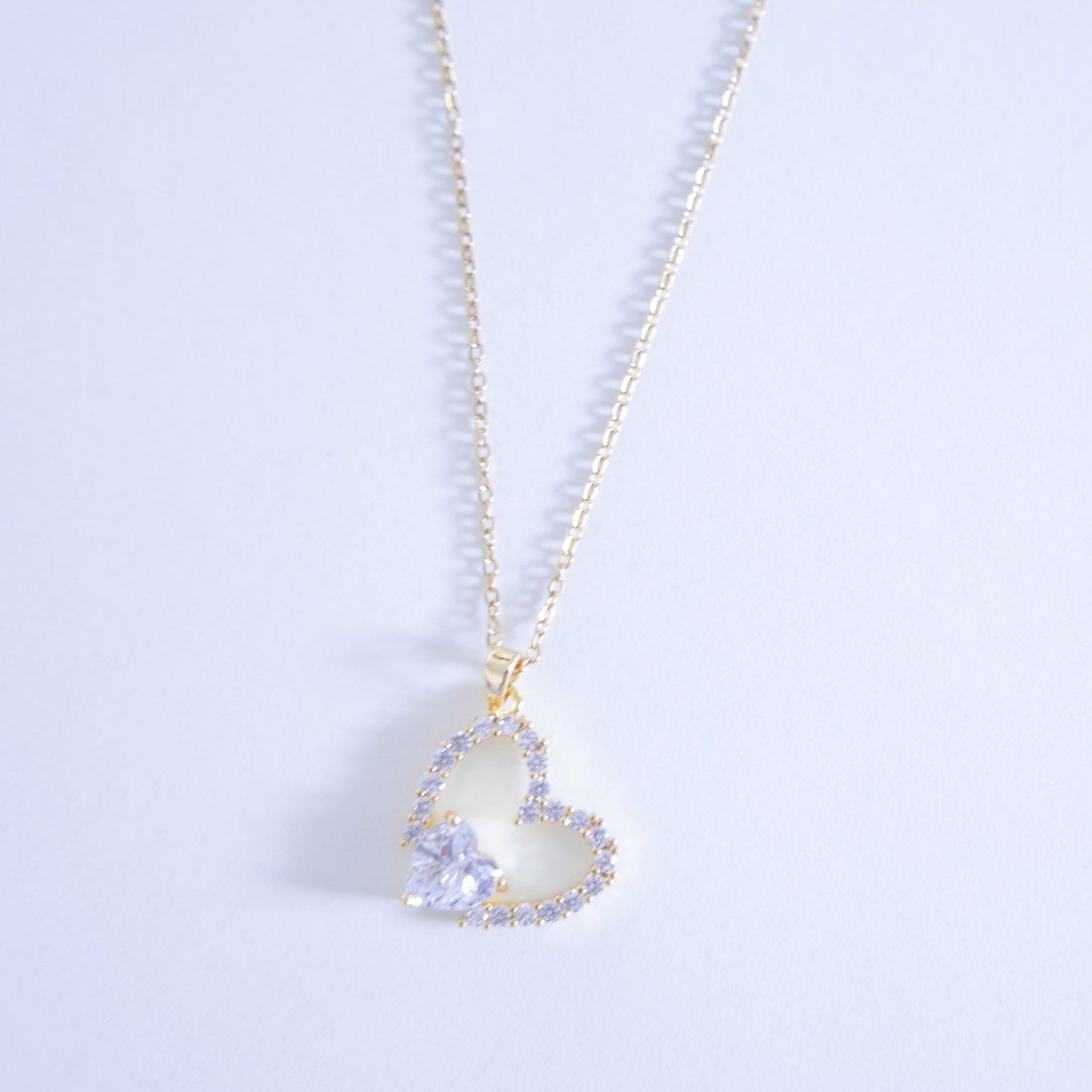 Heart-shaped pendant necklace with a light blue gemstone on a light gray background