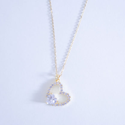 Heart-shaped pendant necklace with a light blue gemstone on a light gray background