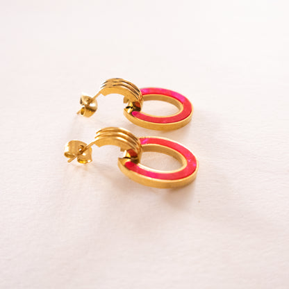 Gold and pink hoop earrings on a light background