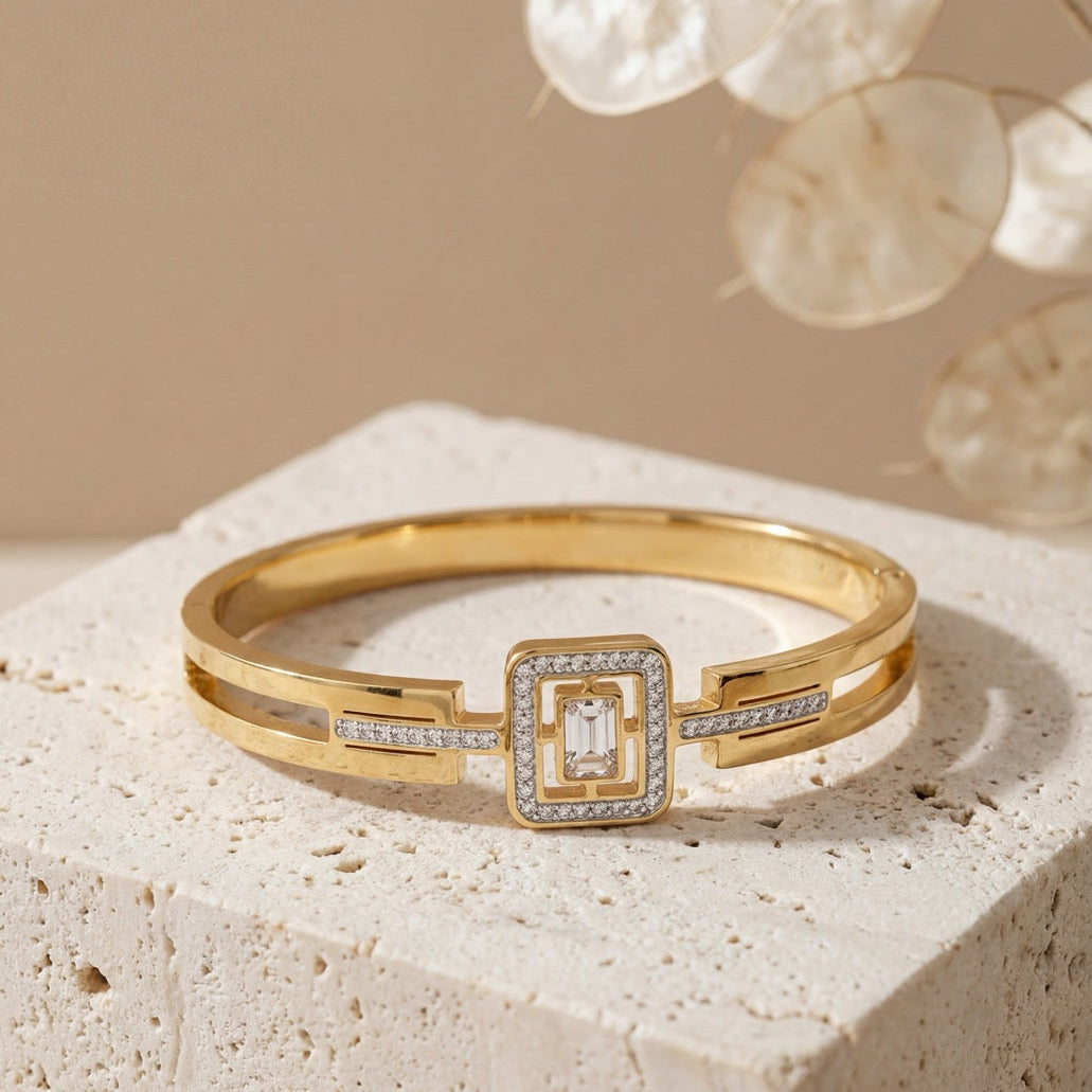 Gold bracelet with diamond accents on a textured surface with a neutral background
