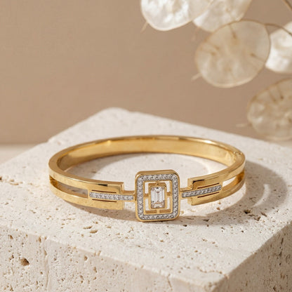 Gold bracelet with diamond accents on a textured surface with a neutral background
