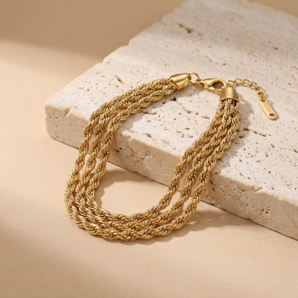 Gold chain bracelet on a textured stone surface