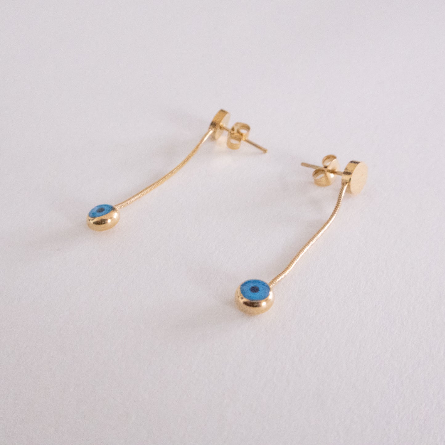 Gold earrings with blue stones on a light gray background
