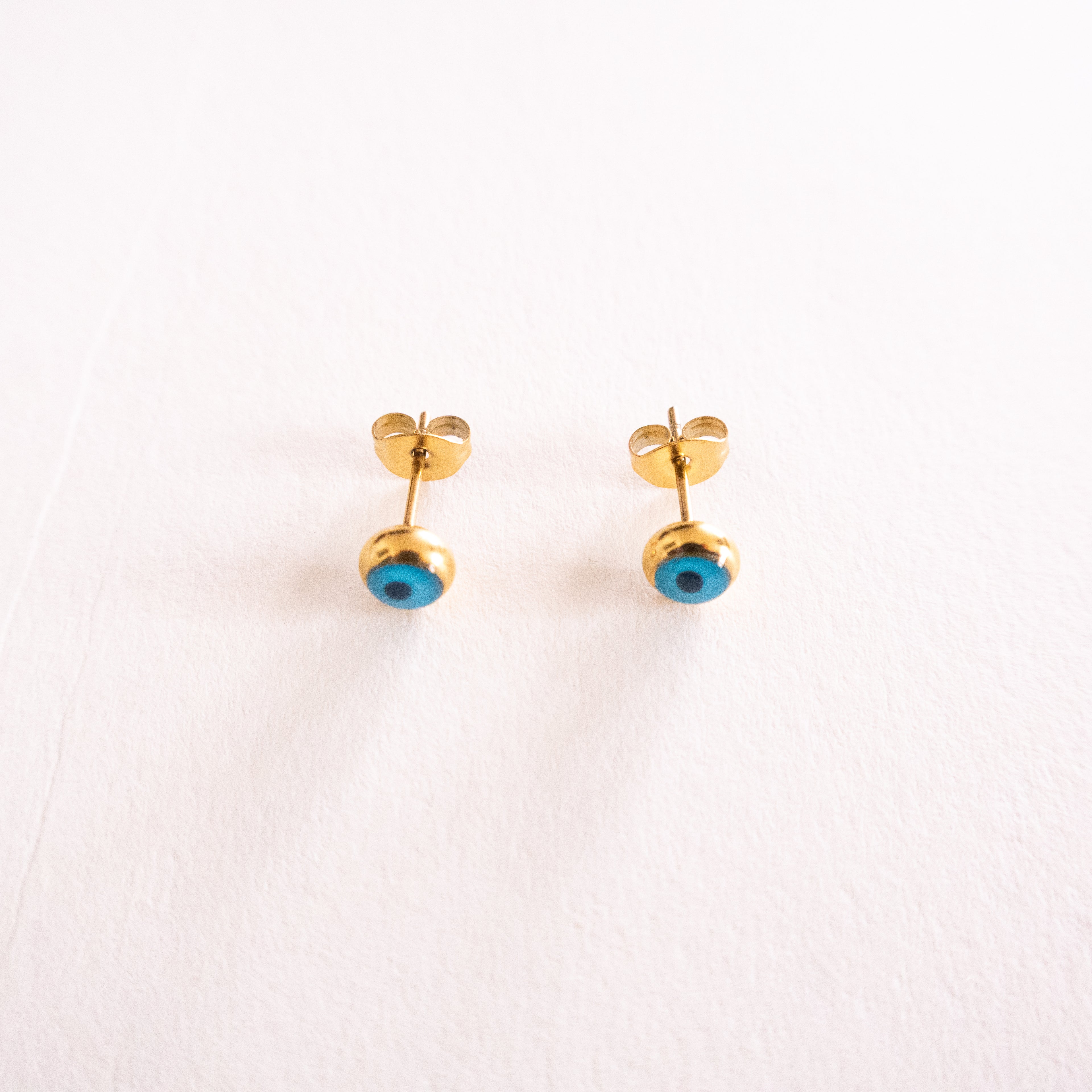 Gold earrings with blue stones on a white background
