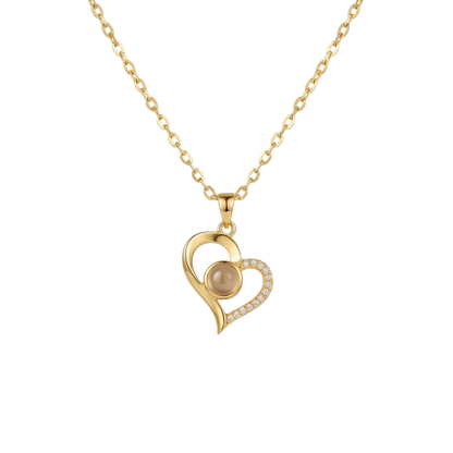 Gold heart-shaped necklace with a pearl center on a white background