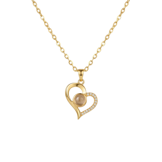 Gold heart-shaped necklace with a pearl center on a white background