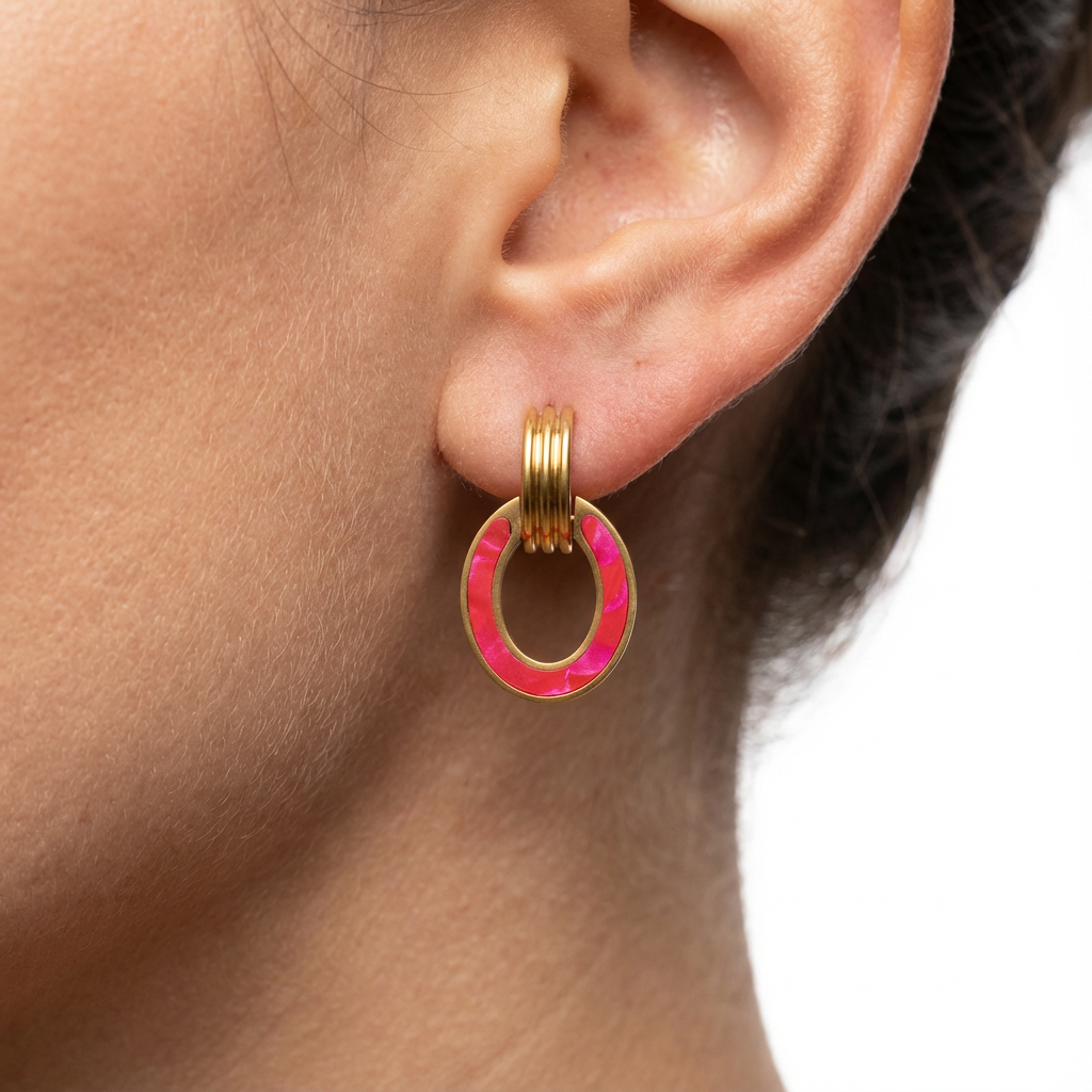 Gold hoop earring with pink center worn by a person