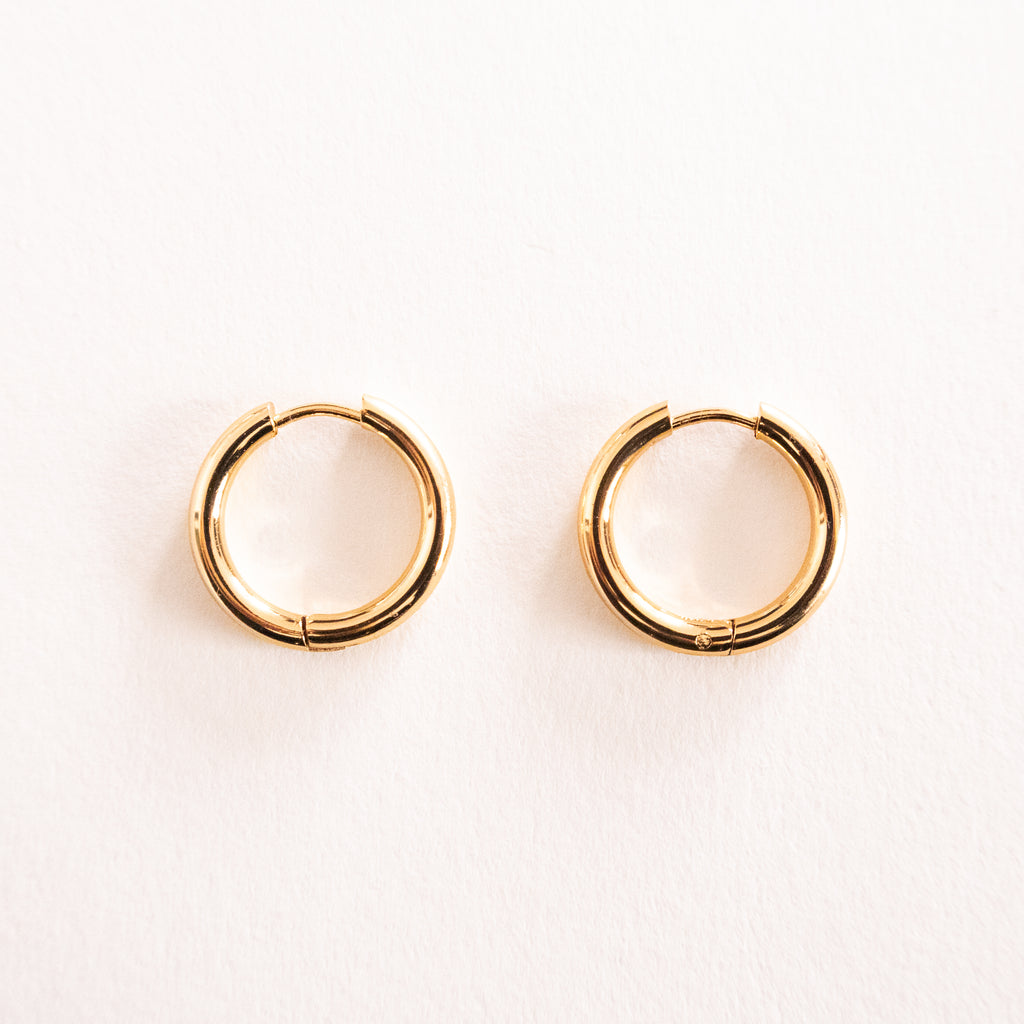Gold hoop earrings on a light pink background