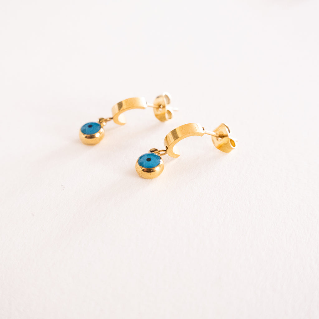 Gold hoop earrings with blue gemstones on a light gray background