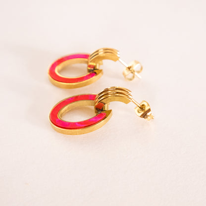 Gold hoop earrings with pink interior on a light beige background
