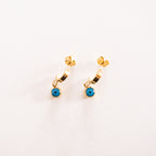 Gold hoop earrings with turquoise stones on a white background