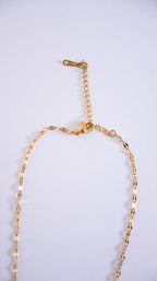Gold necklace on a light gray background