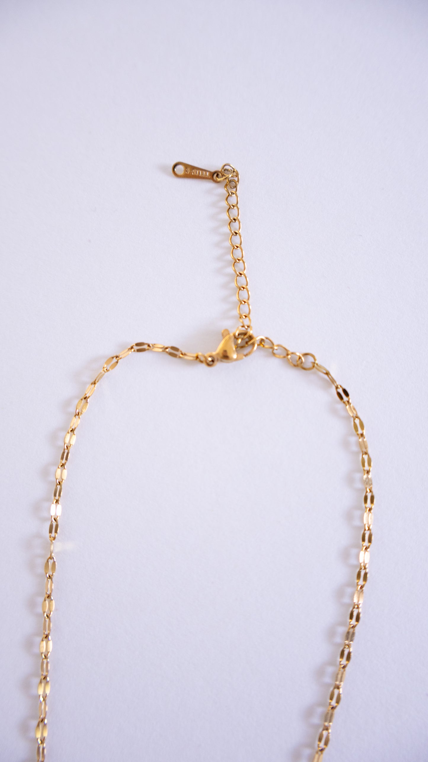 Gold necklace on a light gray background