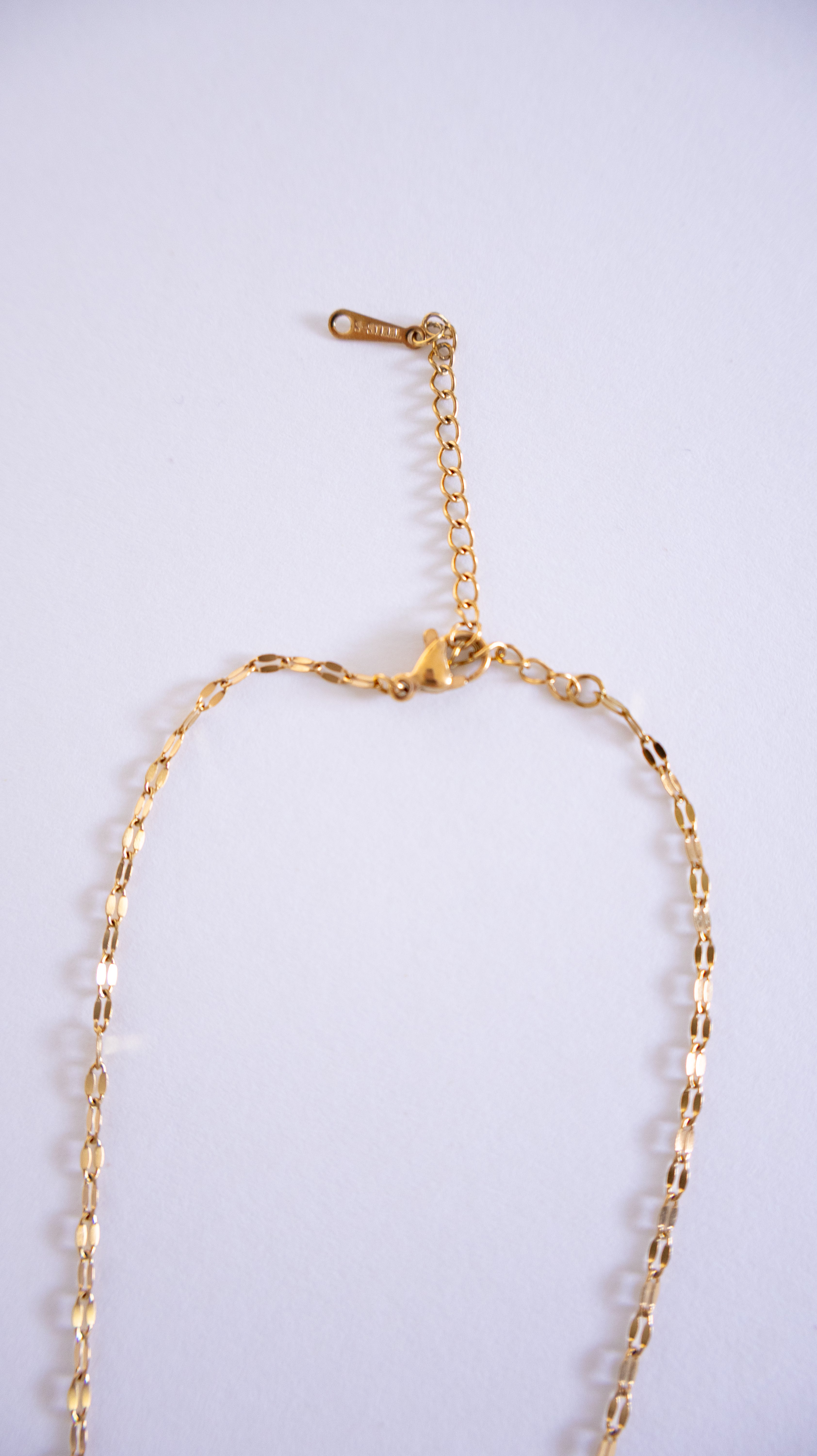 Gold necklace on a light gray background