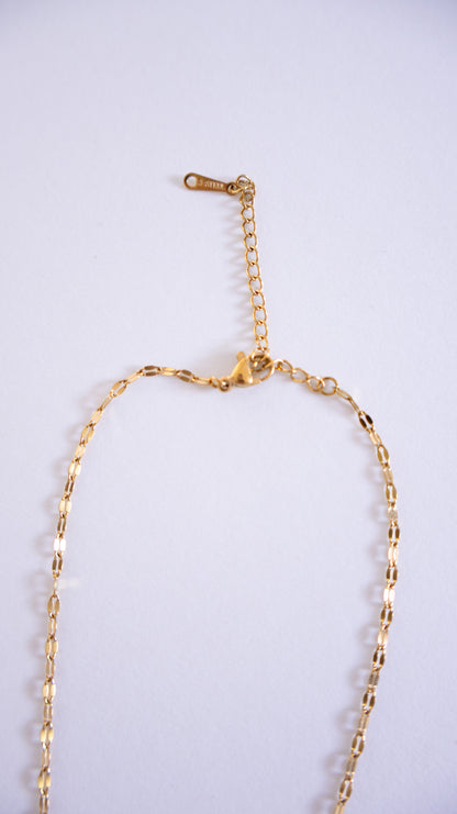 Gold necklace on a light gray background