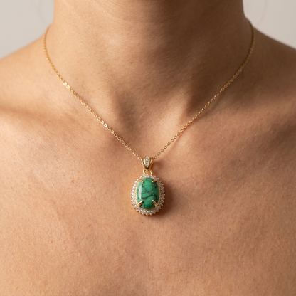 Gold necklace with a green gemstone pendant on a person's neck