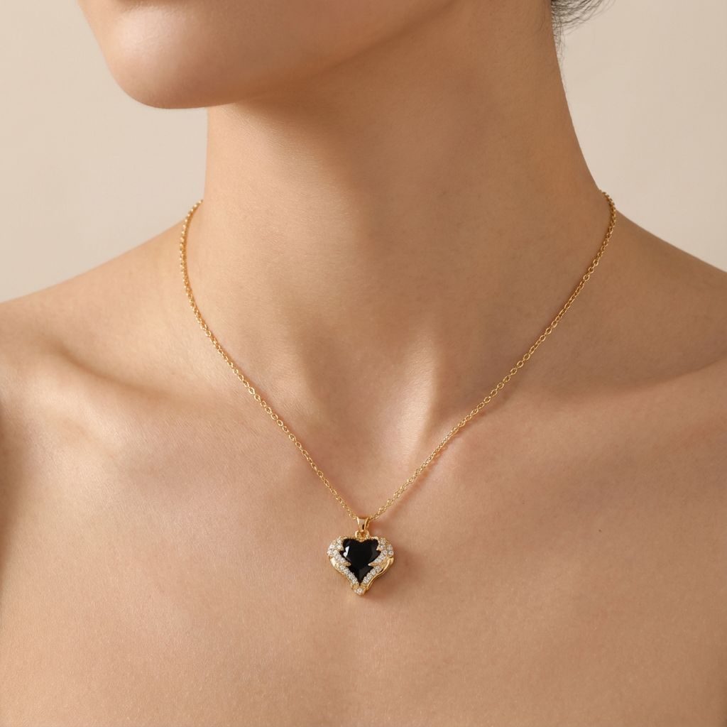 Gold necklace with a heart-shaped pendant featuring a black center and white accents on a person's neck.