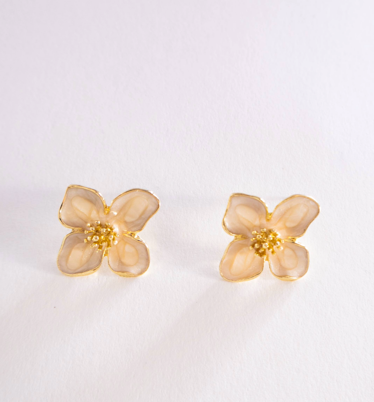 Pair of gold flower-shaped earrings on a light gray background