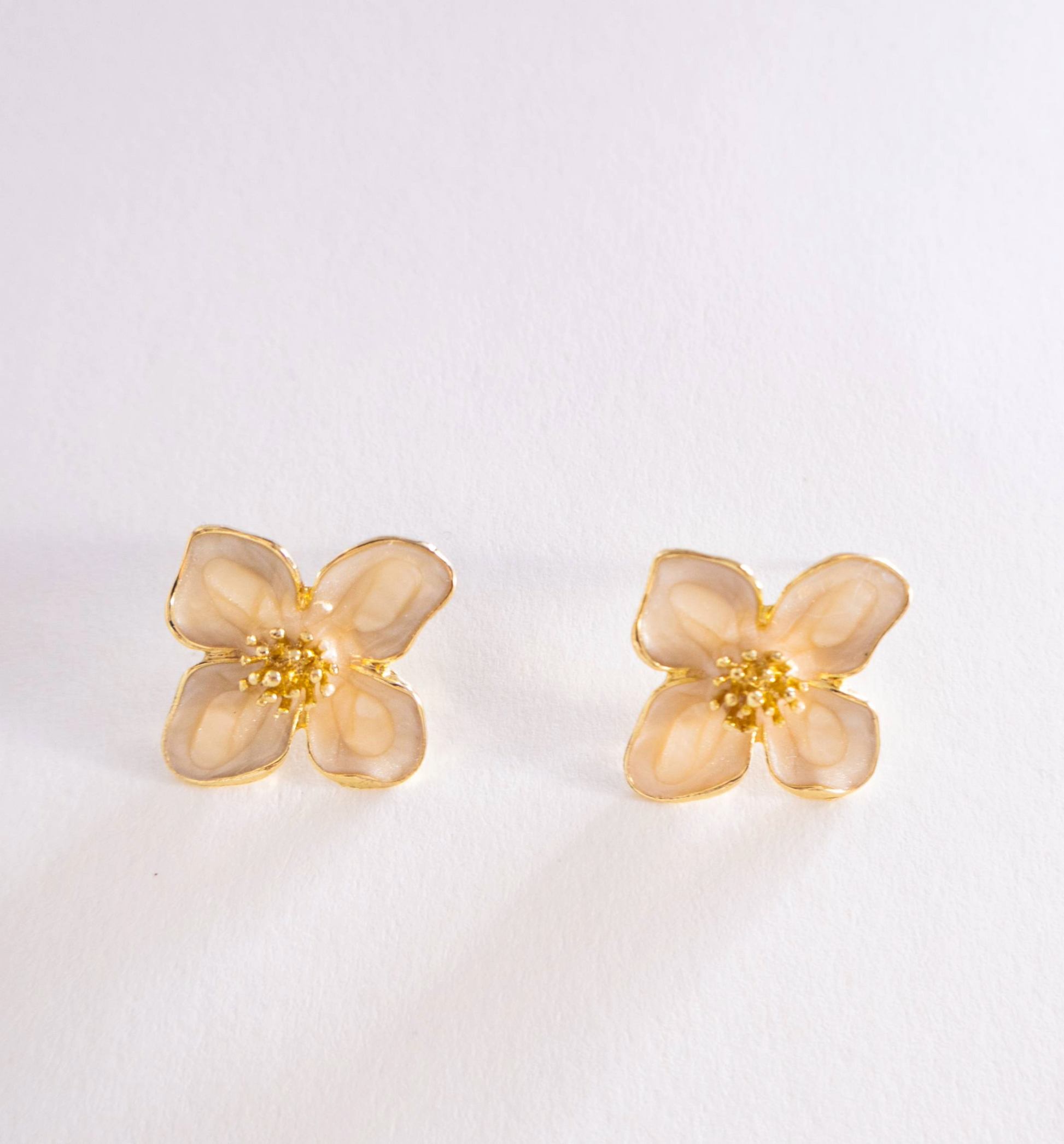 Pair of gold flower-shaped earrings on a light gray background