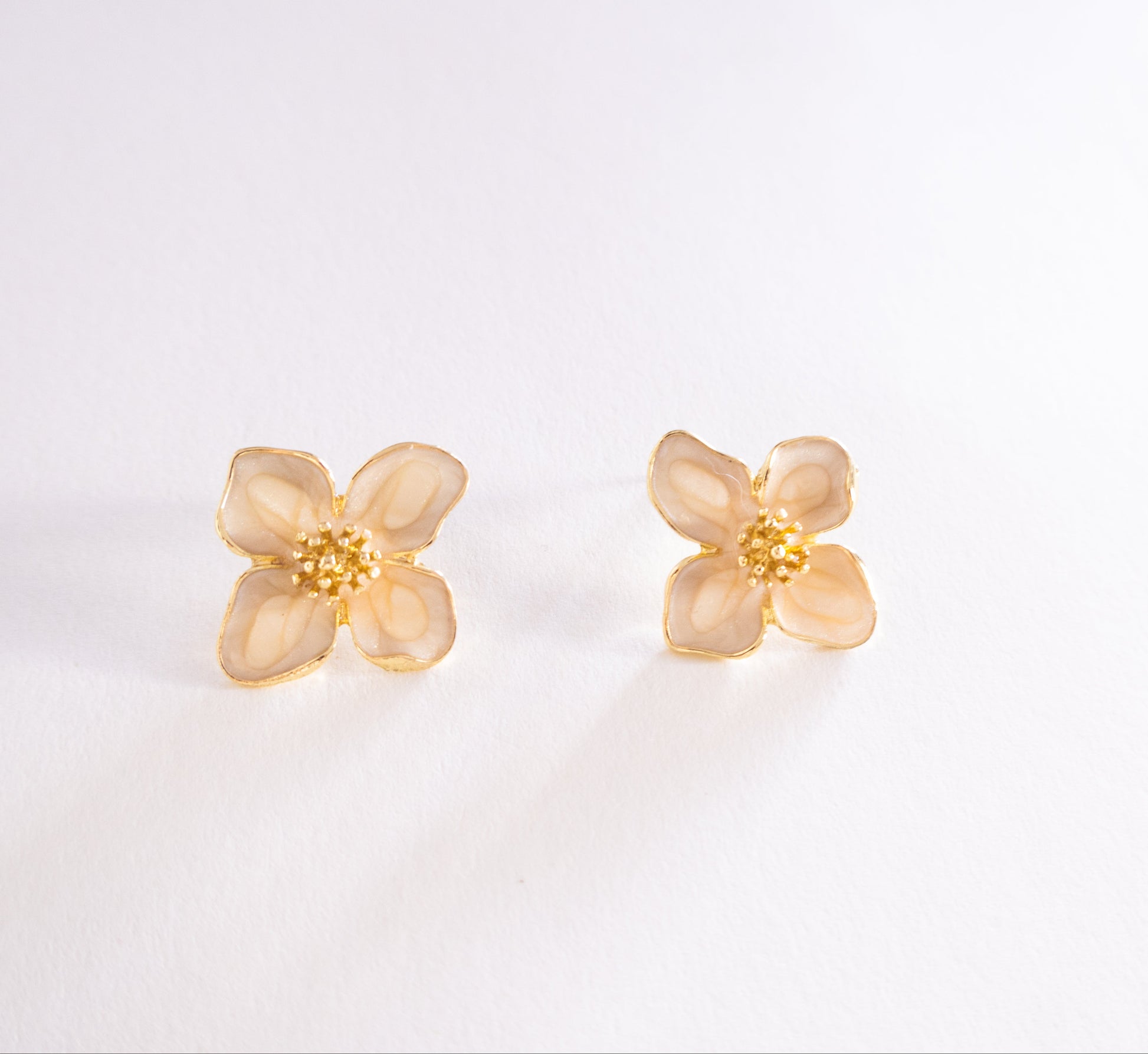 Pair of gold flower-shaped earrings on a light gray background