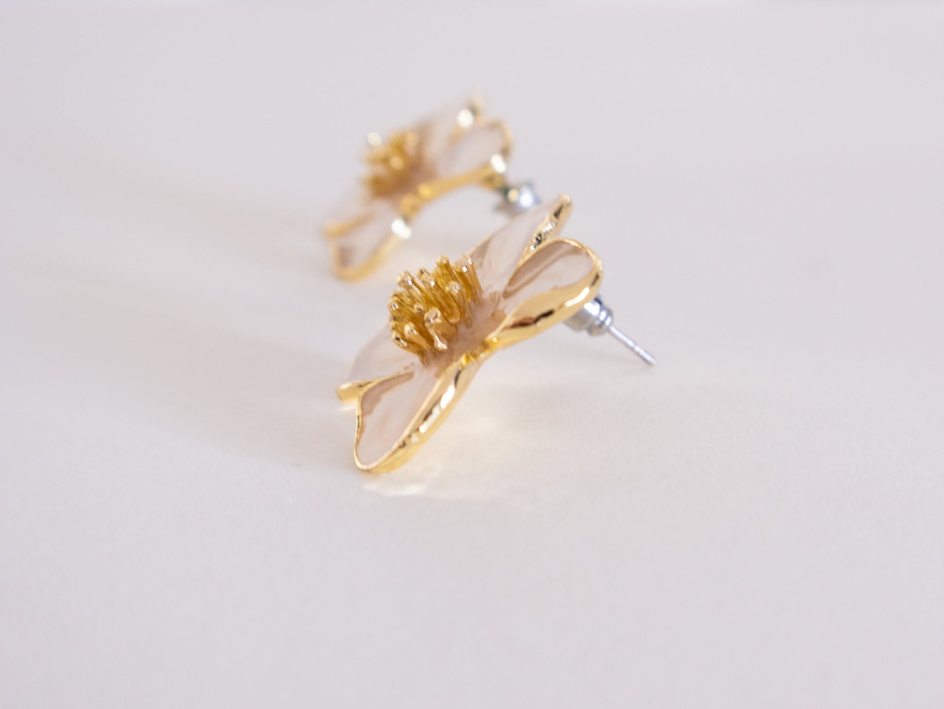 Gold floral earrings on a light gray background